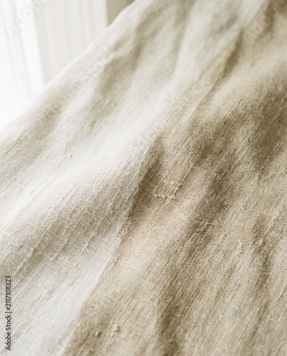 Detailed close-up of natural beige linen fabric with visible texture, subtle wrinkles, and organic weave, ideal for textile backgrounds and design elements