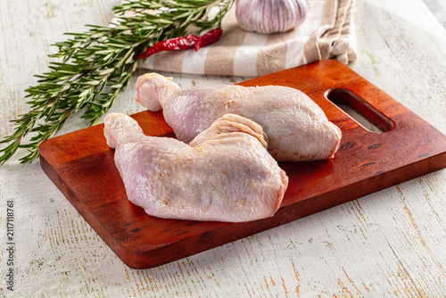 Raw chicken thighs on wooden cutting board with rosemary garlic and chili