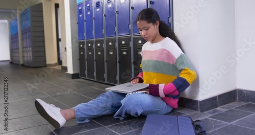 Child wearing sweater closing laptop sliding into blue bag zipping securing at school, copy space