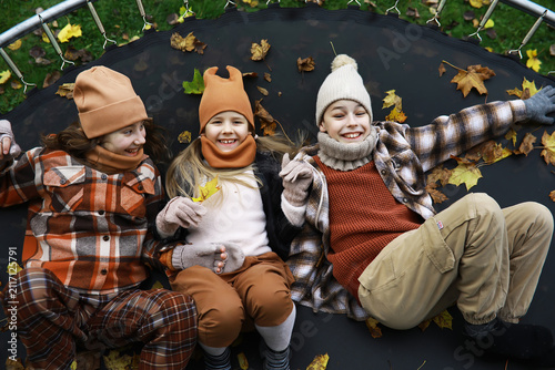 Картината върху платно Children Enjoying Autumn on a Trampoline in Warm Earth-Tone Clothing