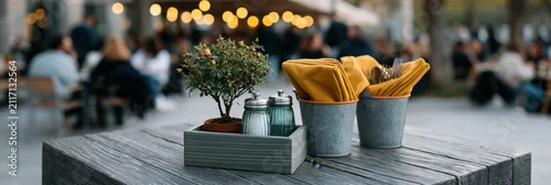 Obraz  z motywem Outdoor picnic style wooden table with potted bonsai and metal napkin buckets with cutlery for restaurant banner and background