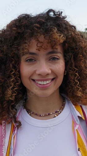 Vertical HD video portrait of smiling young Latin American woman outdoors. Confident millennial female looking at the camera in the city. Lifestyle and wellbeing concept. 
