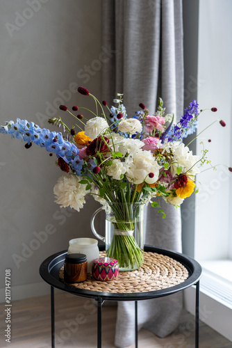 Foto Flower bouquet in glass pitcher vase on table