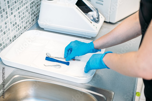 Canvastavla Gloved hands wipe small dental mirror with paper towel on tray before packaging