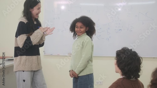 The teacher is teaching young children in a class at school.