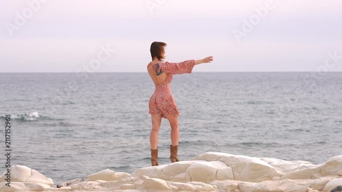 Free woman standing on white rocks enjoying the sea view
