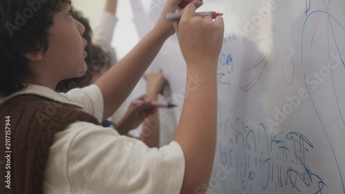 The children are drawing on the whiteboard in the classroom.