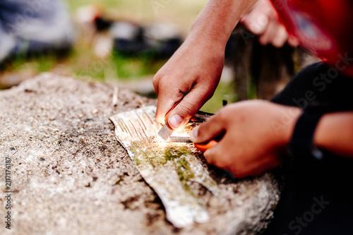 Foto Close up of hands striking a ferro rod to ignite birch bark outdoors