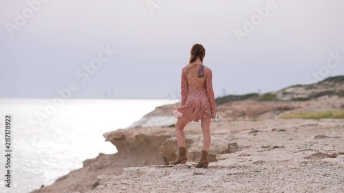 Young woman wandering on a rocky cliff by the sea
