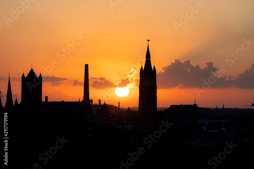 Fotografía The city skyline of Ghent appears in silhouette as the sun rises behind the towers in a blaze of orange in Belgium a dramatic morning view
