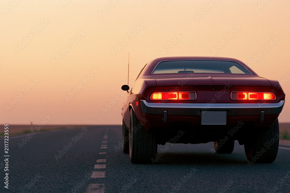 Fototapeta premium The Classic Muscle Car Backlit on an Empty Sunset Road