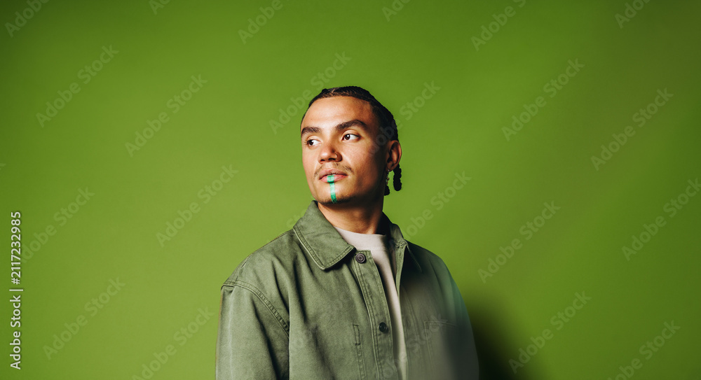 Fototapeta premium Artistic man portrait in the studio with face paint and braided style