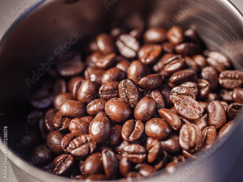 Close-up of freshly roasted coffee beans inside a coffee grinder hopper. Rich texture and aroma for espresso concept
