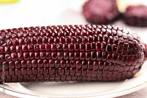Fotografie Black glutinous corn cob with dark purple kernels on plate - sweet sticky rice v