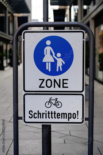 FRANKFURT, GERMANY - APRIL 4, 2026: A close-up shot of a German pedestrian zone street sign with a bicycle restriction notice reading Schritttempo