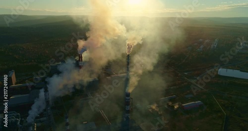 Industrial Plant Releasing Smoke Into Atmosphere. Smoke Billows From the Chimneys of an Industrial Plant Area, Casting a Haze Over the Surrounding landscape