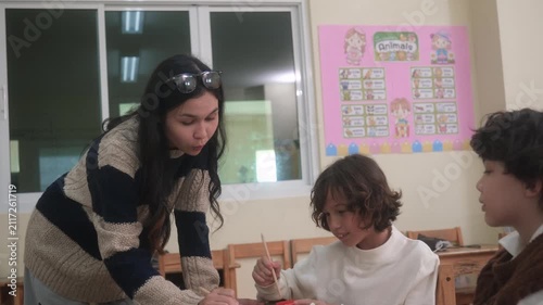 The teacher is teaching young children in a class at school.