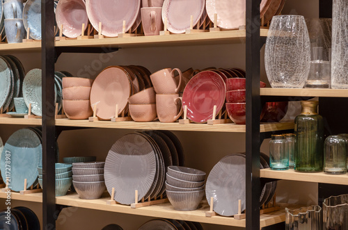 Assorted ceramic plates, bowls, and mugs on wooden store shelves