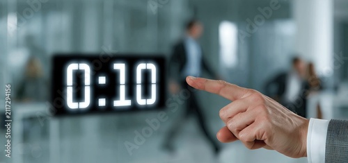 Person pressing a button on a digital timer showing zero, symbolizing urgency and decisive action in an office.