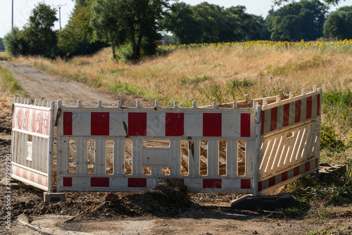 Construction barrier marks closed road near field on sunny day