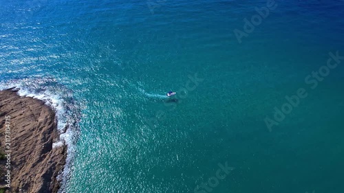 Aerial drone view of a powerful speed boat gliding across crystal-clear turquoise water, creating a striking white wake. Perfect representation of luxury travel, freedom, summer adventure.
