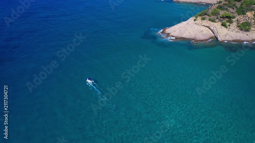 Aerial drone view of a powerful speed boat gliding across crystal-clear turquoise water, creating a striking white wake. Perfect representation of luxury travel, freedom, summer adventure.