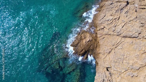 Aerial drone of a peaceful beach in Thassos, Greece, featuring transparent turquoise water, paddleboards, swimmers and a beautiful Mediterranean coastline.