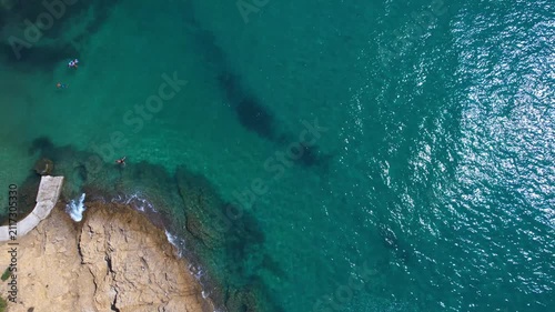 Beautiful aerial view of a sandy beach with crystal clear sea, turquoise water and visitors enjoying swimming and paddleboarding on Thassos Island, Greece.