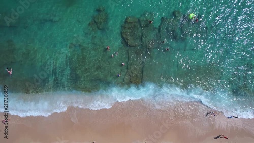 Aerial drone of a peaceful beach in Thassos, Greece, featuring transparent turquoise water, paddleboards, swimmers and a beautiful Mediterranean coastline.