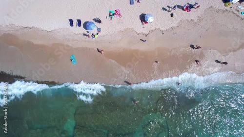 Aerial drone of a peaceful beach in Thassos, Greece, featuring transparent turquoise water, paddleboards, swimmers and a beautiful Mediterranean coastline.