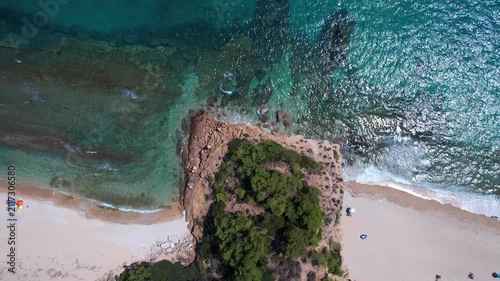 Aerial drone of a peaceful beach in Thassos, Greece, featuring transparent turquoise water, paddleboards, swimmers and a beautiful Mediterranean coastline.