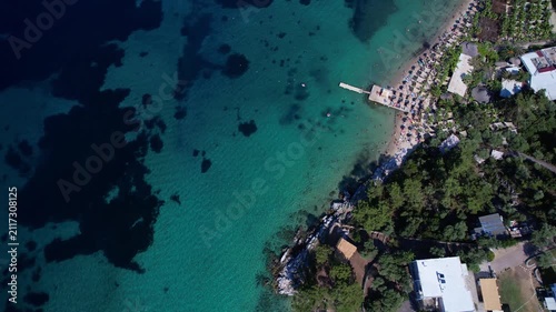 Aerial drone  of a peaceful beach in Thassos, Greece, featuring transparent turquoise water, paddleboards, swimmers and a beautiful Mediterranean coastline.