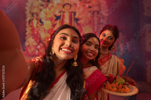 Bengali woman capturing photographs of her mother and sister in Durga Puja pandal