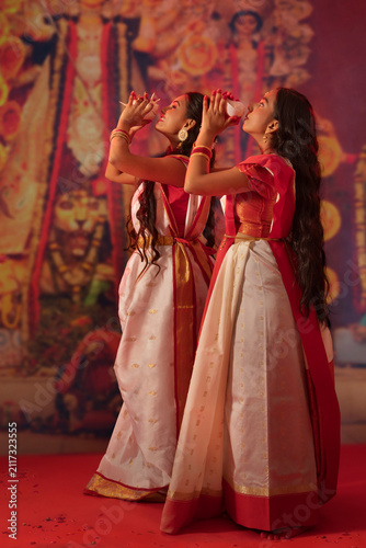 Two Bengali sister playing conch on the occasion of Durga Puja