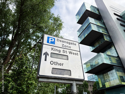 Foto Parking sign for Deansgate zone and King St West near modern glass building in M