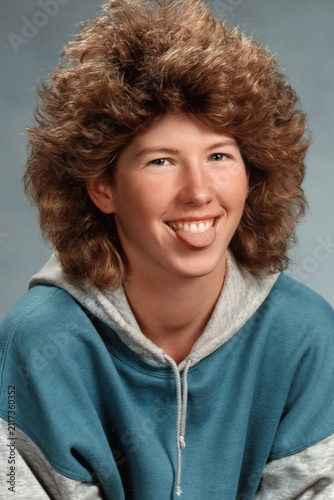 people of ai, yearbook photography of a person with big curly brown mullet, tongue-out grin, wearing teal hoodie, 1980s portrait cyan, photorealistic
