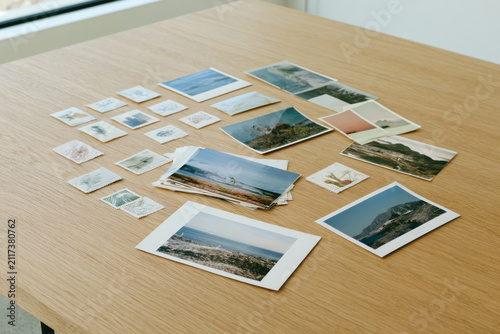 A curated collection of various photographs and nature-themed stamps artfully arranged on a simple wooden table, inviting reflection and appreciation for nature's beauty.