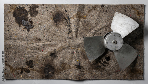 A metal fan blade lies on a stained felt mat