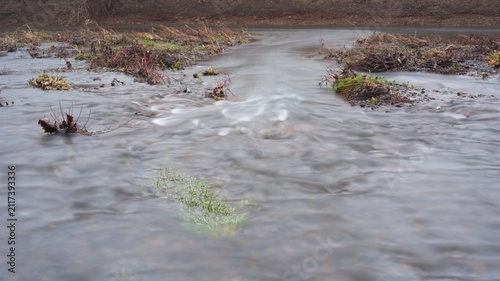 Water stream over gravel shore after flood