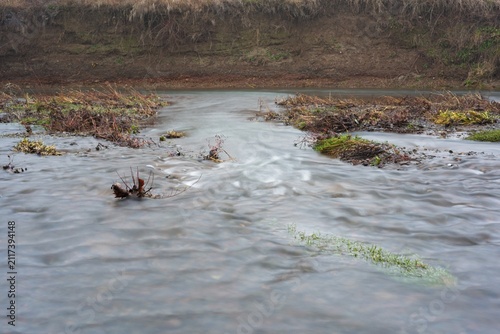 Water stream over gravel shore after flood