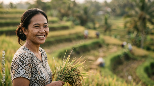 A smiling woman farmer stands in a vibrant rice paddy, holding a bundle of harvested rice stalks, embodying the spirit of rural life and agriculture under a warm, natural light.