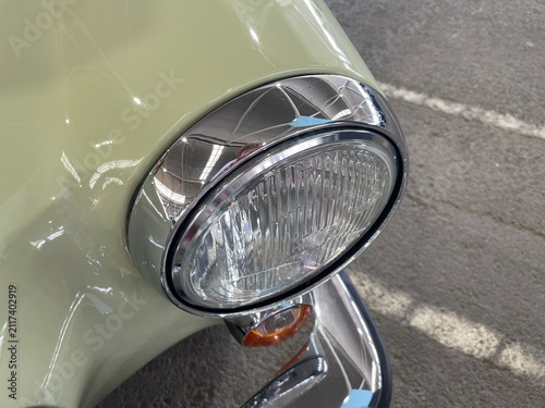 Fotografía Close view of a vintage car headlight and chrome details inside a garage showcas
