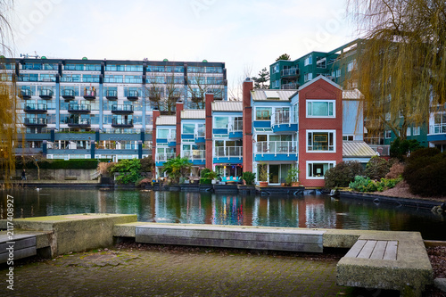 Modern residential waterfront apartment buildings and townhouses reflected in a calm pond on Granville Island, Vancouver, British Columbia, Canada.
