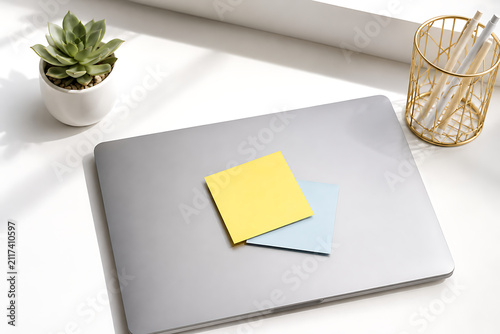 Laptop with sticky notes on white table