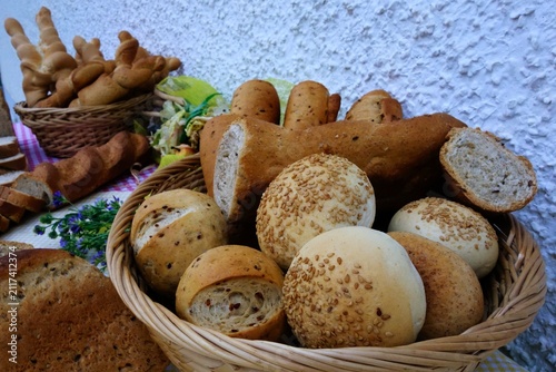 Abundant assortment of freshly baked bread and pastries displayed outdoors on a table. A delightful spread of various baked goods, including loaves, rolls, and twisted breadsticks, arranged for a rust