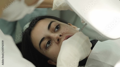 Orthodontist adjusting braces on a young woman's teeth in a dental clinic