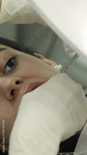 Orthodontist adjusting braces on a young woman's teeth in a dental clinic