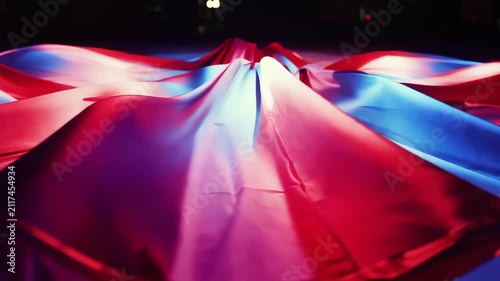 Vibrant abstract fabric waves illuminated with dramatic red and blue neon lights creating a futuristic mood