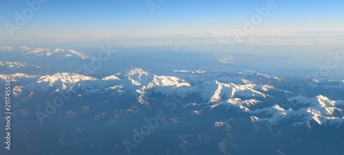 Картината върху платно Sunlit Snow-Covered Mountain Range from High Altitude