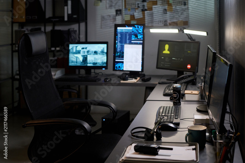 Wide shot of empty security office showing surveillance monitors, communication screen, headset, radio, supporting cybersecurity, monitoring, control room, workplace concepts